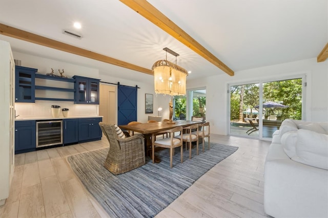 dining space with a barn door, light wood-type flooring, wine cooler, and beam ceiling