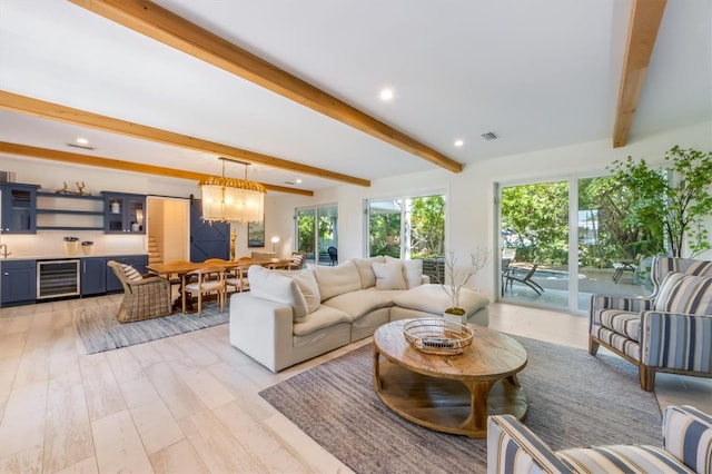 living room featuring beam ceiling, light hardwood / wood-style flooring, wine cooler, and a chandelier