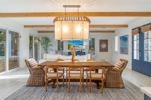 dining room with beam ceiling, a healthy amount of sunlight, and hardwood / wood-style floors