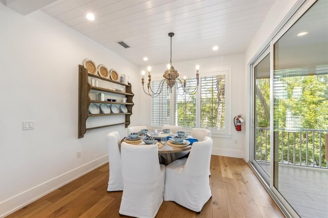 dining area with wood-type flooring and an inviting chandelier