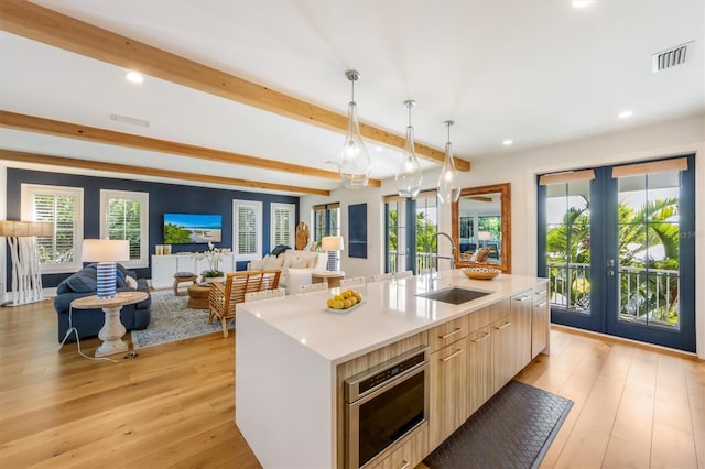 kitchen with french doors, light hardwood / wood-style flooring, and a center island with sink