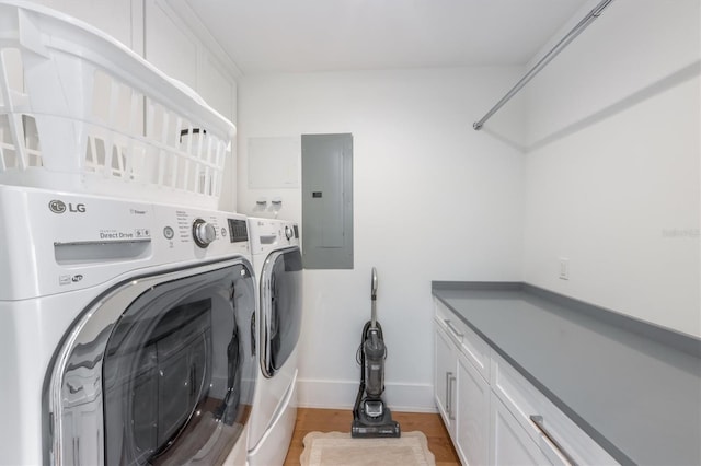 clothes washing area featuring cabinets, light hardwood / wood-style flooring, electric panel, and washing machine and dryer