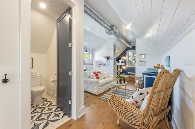 interior space featuring toilet, vaulted ceiling, and wood-type flooring