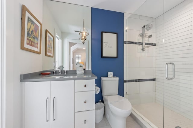 bathroom featuring a shower with door, vanity, tile patterned flooring, and toilet