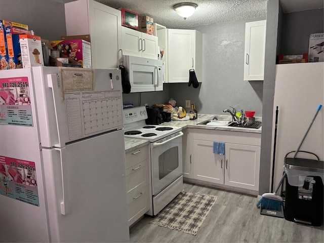 kitchen featuring light hardwood / wood-style flooring, white cabinetry, sink, white appliances, and a textured ceiling