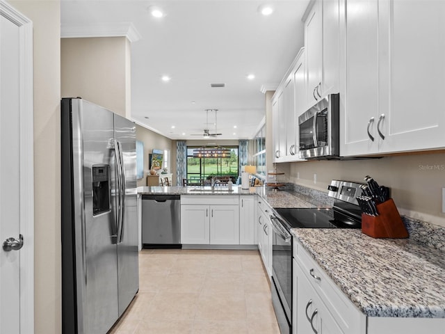 kitchen with light stone counters, stainless steel appliances, kitchen peninsula, and white cabinets