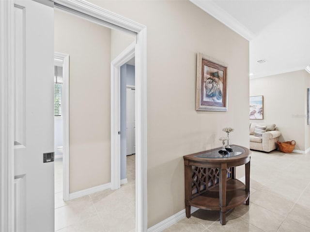 hall with ornamental molding and light tile floors