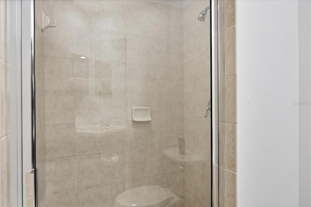 bathroom featuring a shower with door and toilet