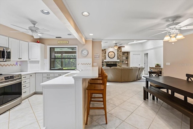 kitchen featuring a breakfast bar, white cabinets, sink, a fireplace, and stainless steel appliances