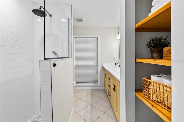 bathroom with tiled shower, vanity, and tile patterned flooring