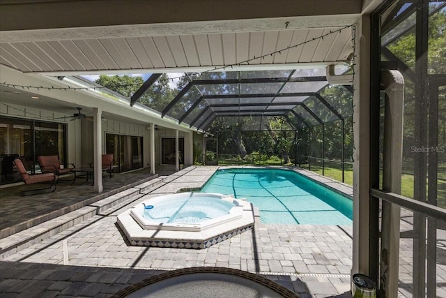 view of swimming pool featuring ceiling fan, a patio, glass enclosure, and an in ground hot tub