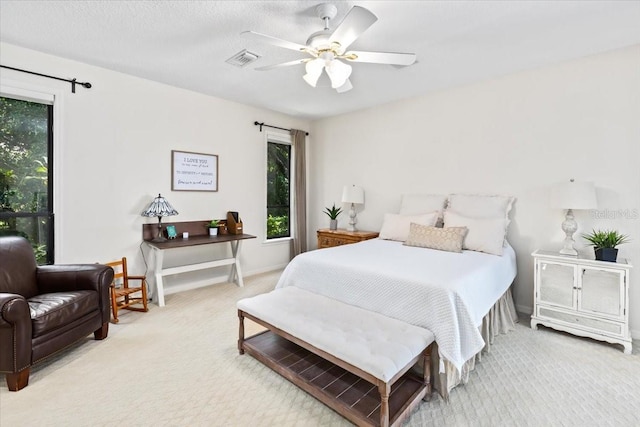 bedroom with ceiling fan, multiple windows, light carpet, and a textured ceiling