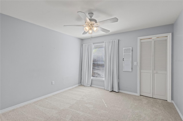 unfurnished bedroom with ceiling fan, a closet, and light carpet