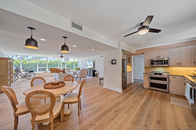 dining room featuring a textured ceiling, ceiling fan, light wood-type flooring, and sink