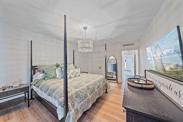 bedroom featuring hardwood / wood-style flooring, a notable chandelier, and a textured ceiling