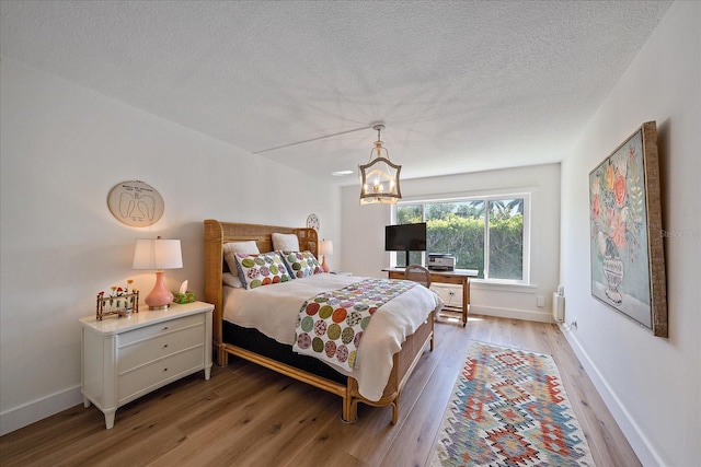 bedroom featuring radiator heating unit, a textured ceiling, and light hardwood / wood-style flooring