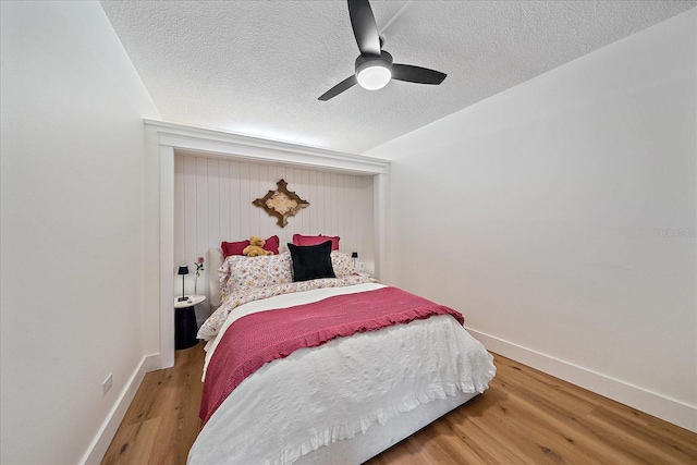 bedroom with ceiling fan, wood-type flooring, and a textured ceiling