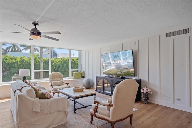 living room with ceiling fan, a textured ceiling, a wealth of natural light, and light hardwood / wood-style flooring