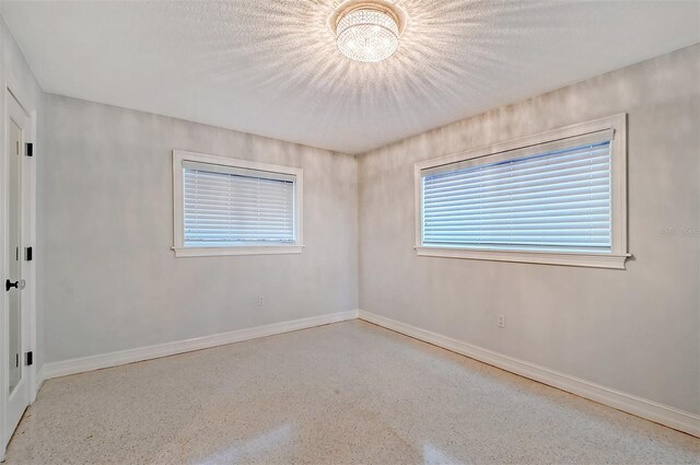 spare room with a textured ceiling and an inviting chandelier