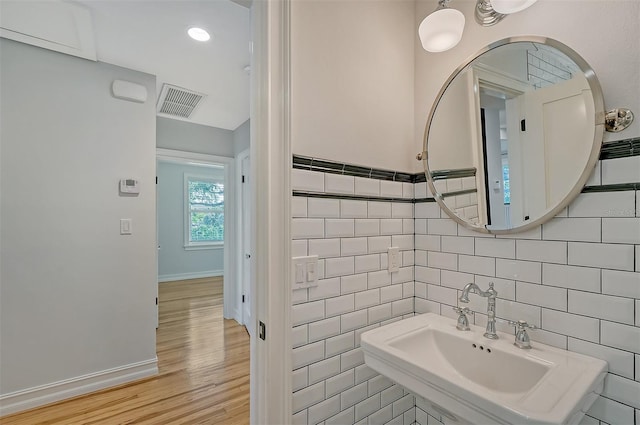 bathroom featuring sink, wood-type flooring, and tile walls