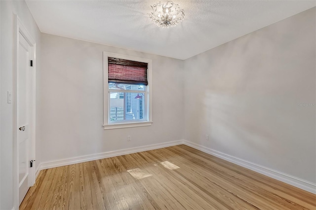 empty room featuring a chandelier and light wood-type flooring