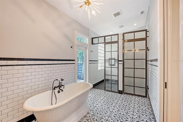 bathroom featuring a bath, tile walls, and a notable chandelier