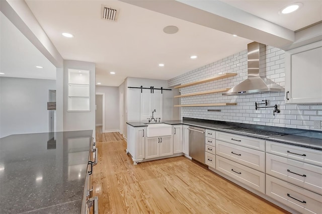 kitchen featuring white cabinetry, sink, wall chimney exhaust hood, stainless steel dishwasher, and stovetop