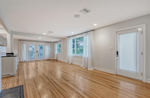 unfurnished living room featuring french doors and light hardwood / wood-style floors