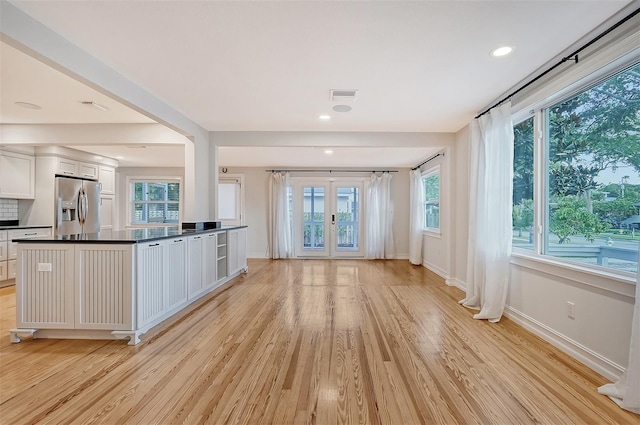 kitchen featuring white cabinets, stainless steel fridge, light wood-type flooring, and a wealth of natural light