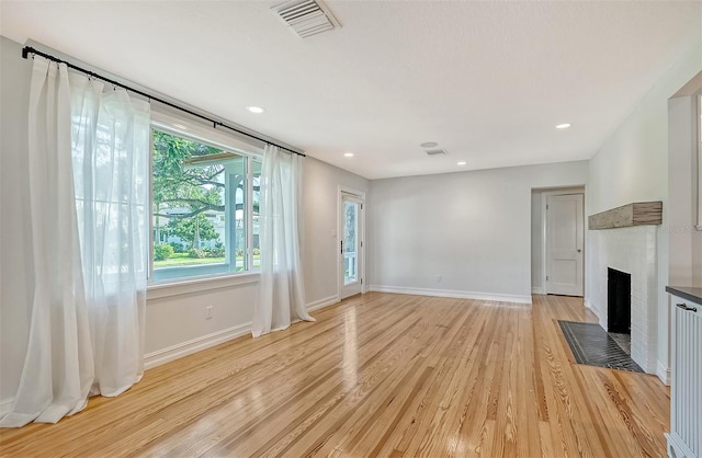 unfurnished living room with a fireplace and light hardwood / wood-style flooring