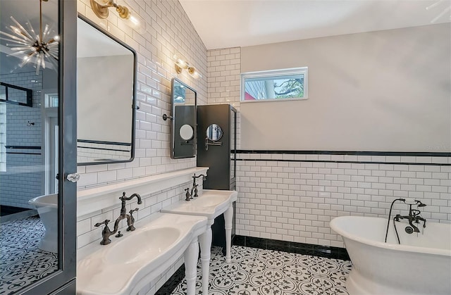 bathroom featuring tile patterned flooring, a bathtub, tile walls, and sink