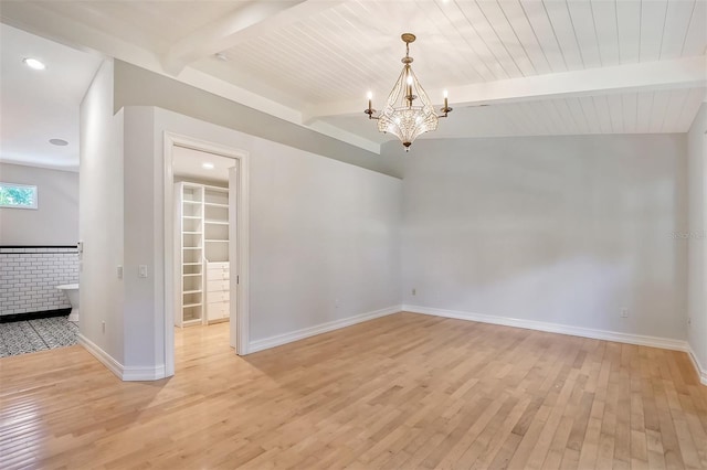 unfurnished room featuring beamed ceiling, a chandelier, and light hardwood / wood-style floors