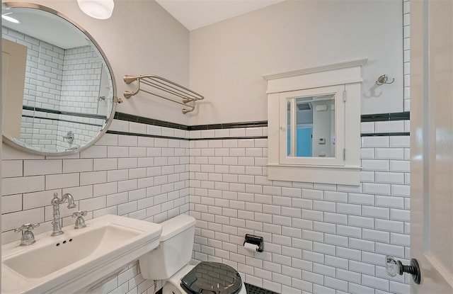 bathroom featuring toilet, sink, and tile walls