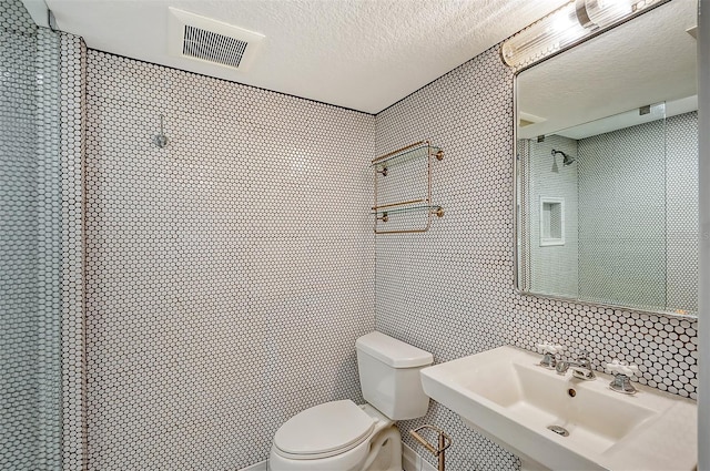 bathroom featuring tasteful backsplash, a textured ceiling, sink, a shower, and toilet