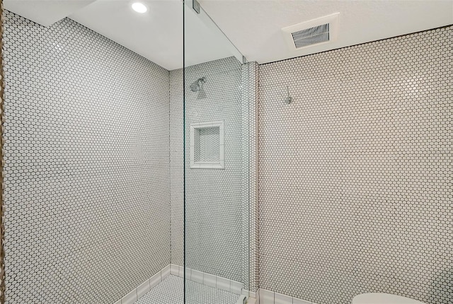 interior space with tile patterned floors, toilet, and tiled shower