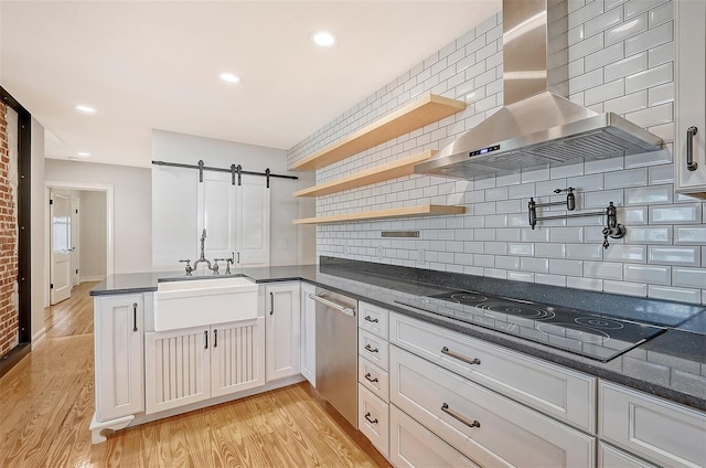 kitchen with decorative backsplash, white cabinetry, sink, and wall chimney exhaust hood