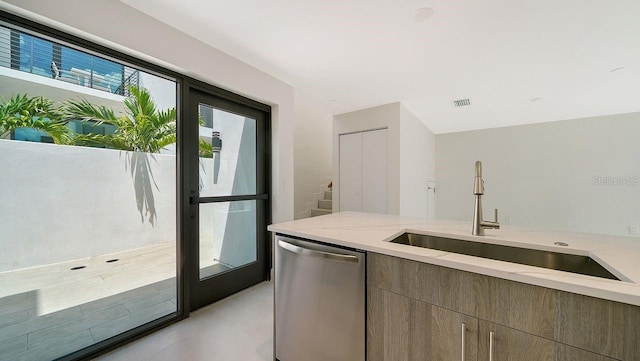 kitchen with light stone counters, sink, and stainless steel dishwasher