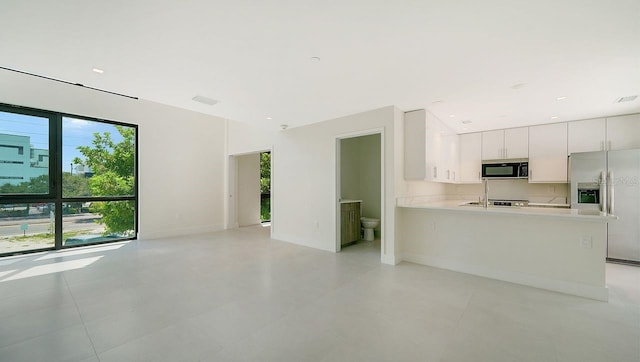 kitchen featuring stainless steel fridge, visible vents, white cabinets, a peninsula, and light countertops