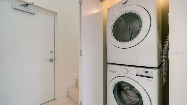 laundry area featuring light tile patterned flooring and stacked washer / drying machine