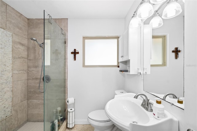 bathroom with toilet, a tile shower, and sink