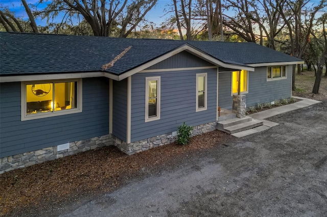 view of front of home with roof with shingles, crawl space, and driveway