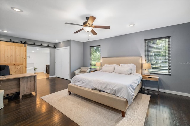 bedroom featuring a barn door, recessed lighting, a ceiling fan, baseboards, and hardwood / wood-style floors