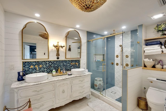 bathroom with vanity, toilet, a shower with door, and tile walls