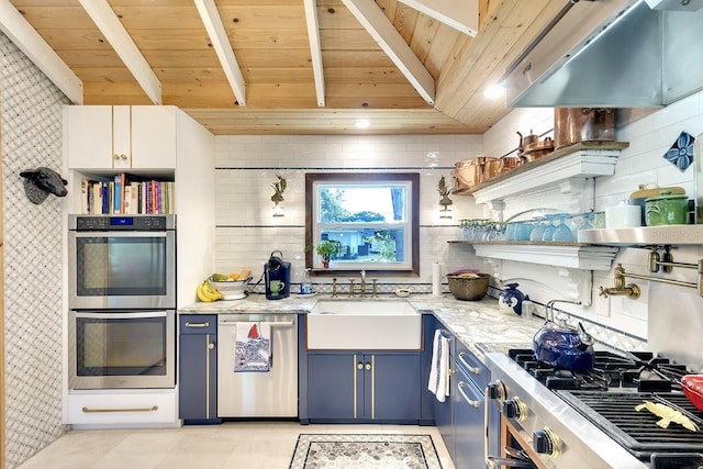 kitchen with light stone countertops, sink, stainless steel appliances, blue cabinets, and white cabinets