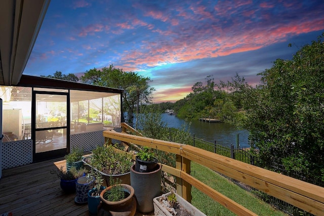 deck at dusk with a sunroom and a water view