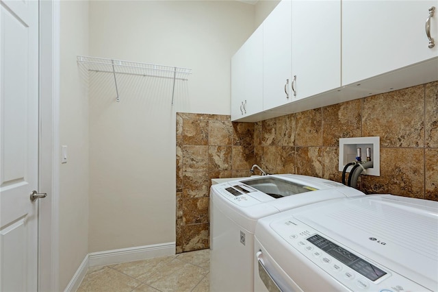 clothes washing area with cabinets, light tile patterned floors, and washing machine and clothes dryer