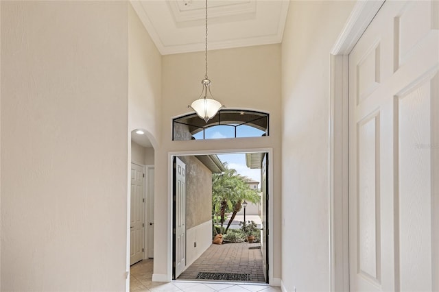 foyer featuring a towering ceiling, crown molding, and light tile patterned floors