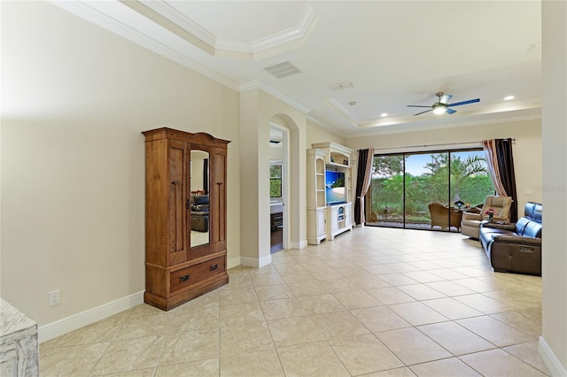 tiled living room featuring a raised ceiling, ceiling fan, and ornamental molding