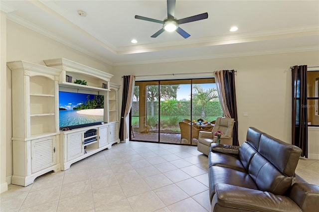 living room featuring crown molding, ceiling fan, built in shelves, a tray ceiling, and light tile patterned flooring