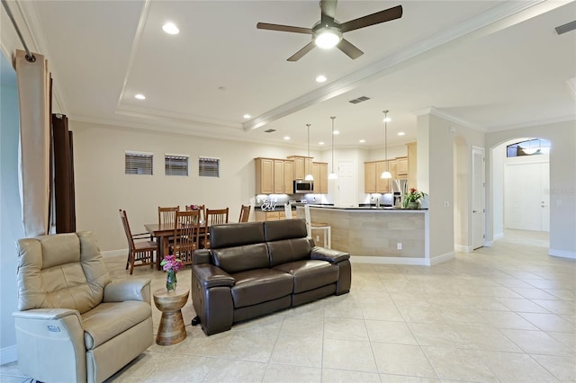 tiled living room with a raised ceiling, ceiling fan, and crown molding